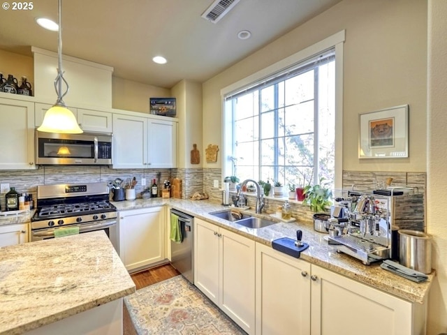 kitchen with hanging light fixtures, a sink, visible vents, appliances with stainless steel finishes, and tasteful backsplash