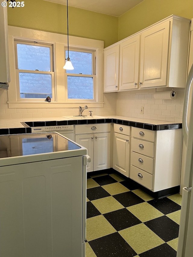 2127 NW Irving St # 202, Portland, OR 97210 - kitchen featuring tile countertops, dark floors, washer / clothes dryer, and decorative backsplash