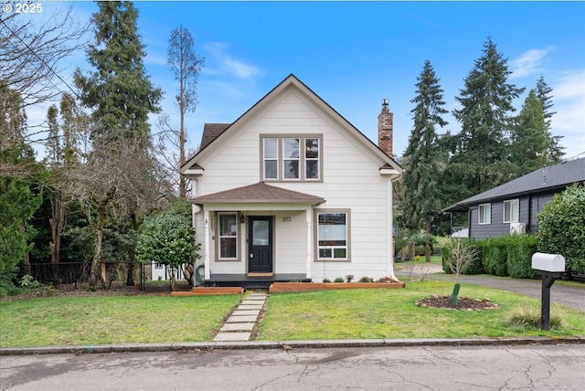 view of front facade featuring a front lawn, a chimney, a shingled roof, and fence