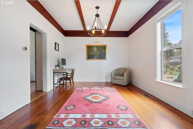 interior space with wood-type flooring, visible vents, a chandelier, beamed ceiling, and baseboards