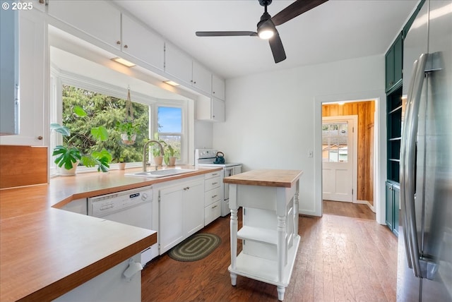 kitchen featuring wooden counters, white appliances, a sink, and white cabinets