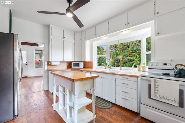 kitchen with open shelves, a wealth of natural light, butcher block counters, white cabinetry, and white appliances