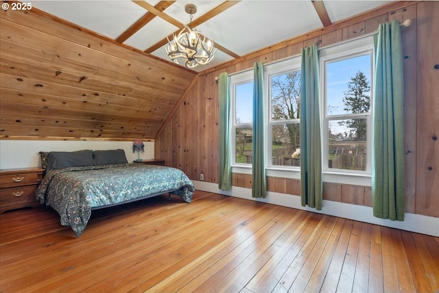 bedroom featuring wood walls, a notable chandelier, vaulted ceiling, and hardwood / wood-style floors