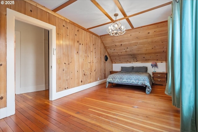 unfurnished bedroom featuring lofted ceiling, wood walls, a chandelier, baseboards, and hardwood / wood-style flooring