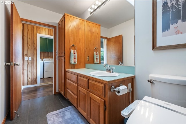 bathroom with toilet, vanity, washer and dryer, and wood finished floors