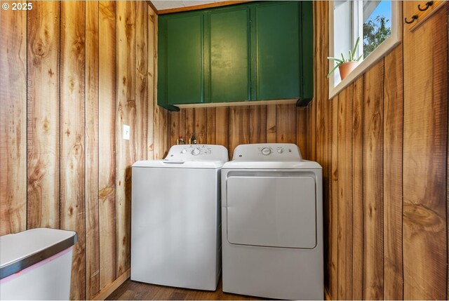 laundry room featuring cabinet space, washer and dryer, and wood walls