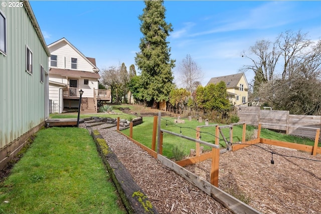 view of yard with a vegetable garden, stairs, fence, and a deck