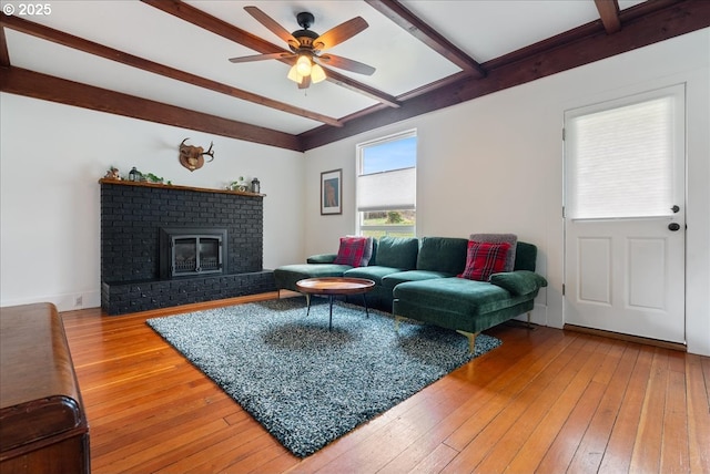 living room featuring a ceiling fan, a fireplace, beamed ceiling, and hardwood / wood-style floors