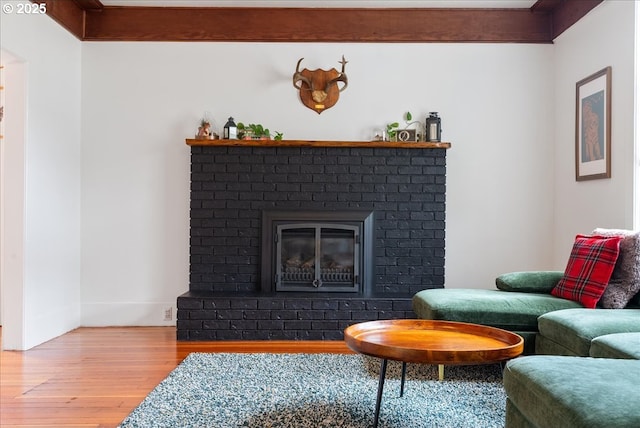 living area featuring a brick fireplace, baseboards, and light wood finished floors