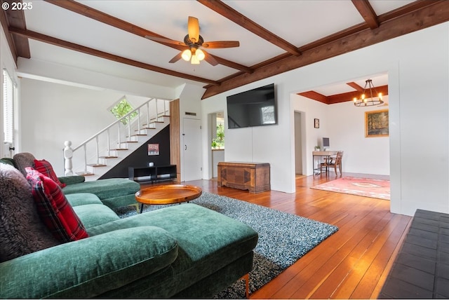 living room with beamed ceiling, stairway, hardwood / wood-style floors, and ceiling fan with notable chandelier