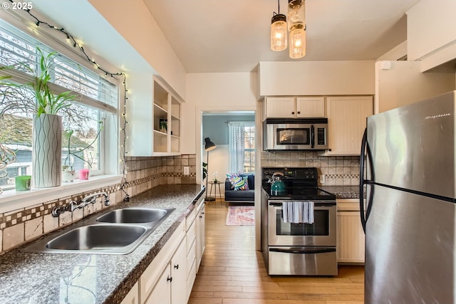 kitchen featuring sink, appliances with stainless steel finishes, hanging light fixtures, backsplash, and light wood-type flooring