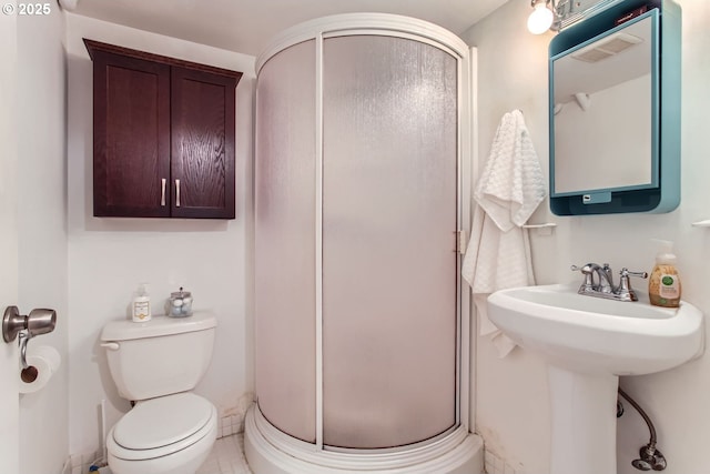 bathroom featuring sink, toilet, and a shower with door