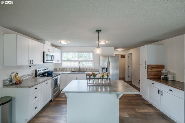 2261 Fulton Pl SE, Albany, OR 97322 - kitchen with stainless steel appliances, a sink, white cabinetry, a kitchen island, and dark wood-style floors