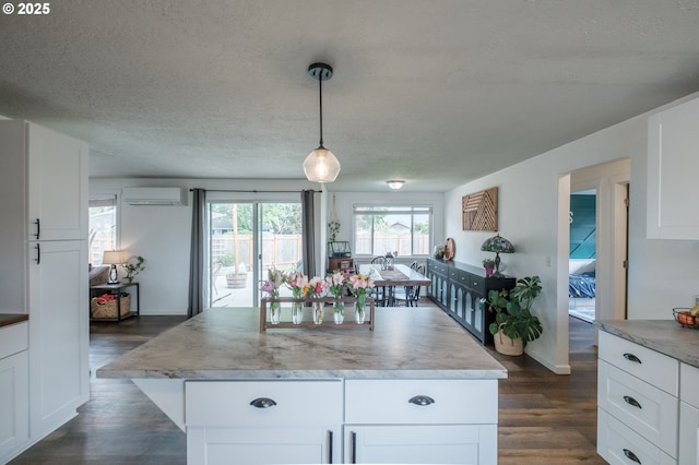 2261 Fulton Pl SE, Albany, OR 97322 - kitchen featuring dark wood-type flooring, a wall unit AC, white cabinetry, a textured ceiling, and baseboards