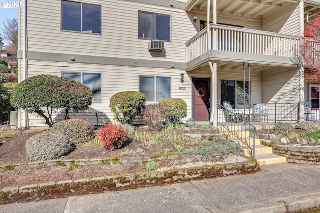 view of front of home with a balcony and a wall unit AC