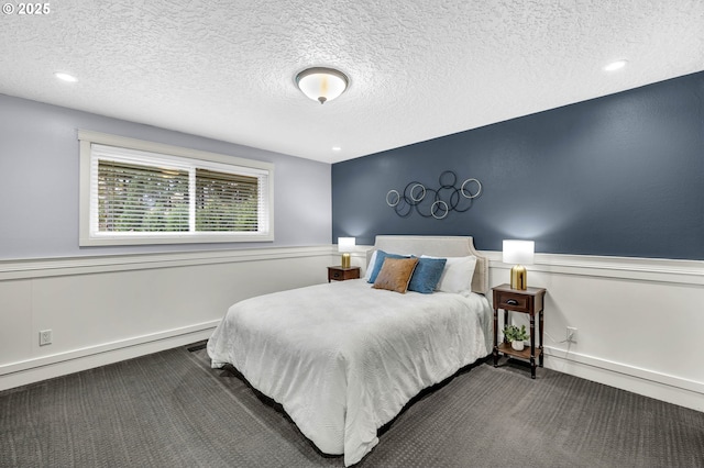 bedroom with a baseboard radiator, a textured ceiling, and dark carpet