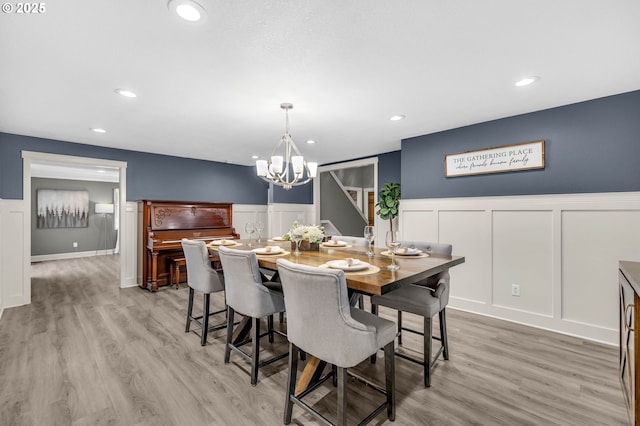 dining space with a wainscoted wall, light wood-style flooring, a decorative wall, and recessed lighting