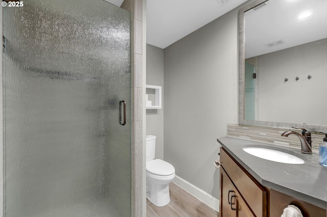 bathroom featuring baseboards, toilet, wood finished floors, vanity, and a shower stall