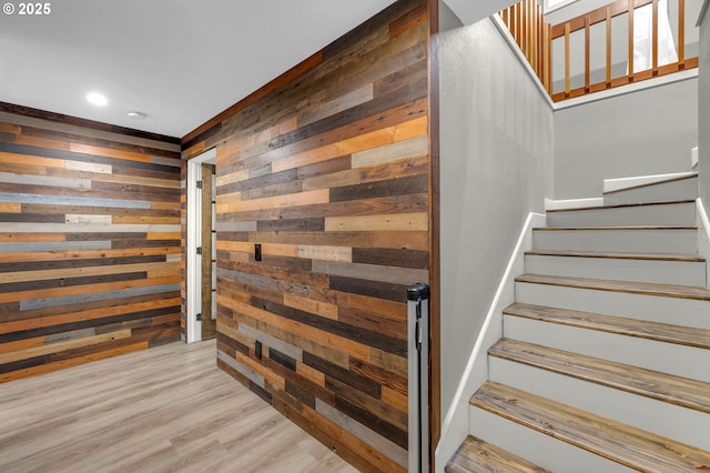 stairway with wooden walls and hardwood / wood-style floors