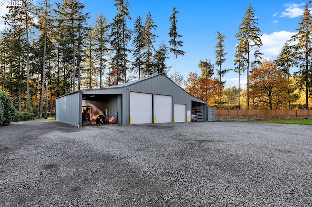 garage with a garage, fence, and gravel driveway