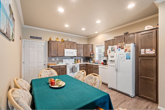 kitchen featuring white appliances, light countertops, crown molding, and light wood-style flooring