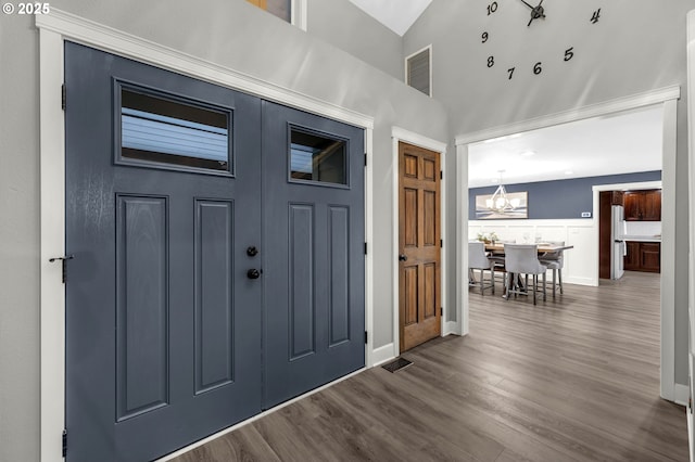 entryway featuring an inviting chandelier, high vaulted ceiling, and dark hardwood / wood-style floors