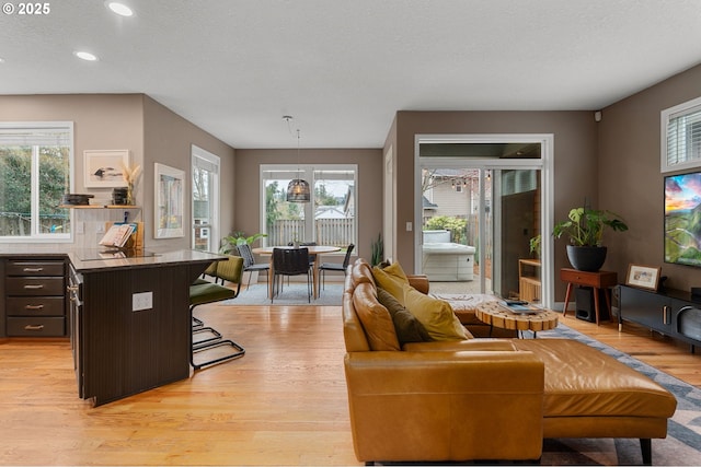 living room with recessed lighting, light wood-type flooring, and a textured ceiling