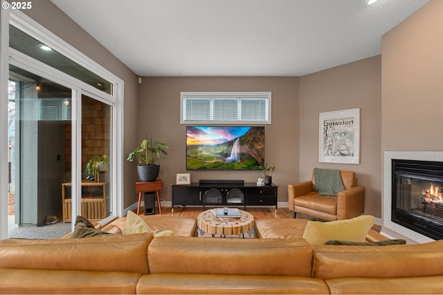 living room with a tiled fireplace, plenty of natural light, baseboards, and wood finished floors