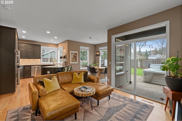 living room featuring visible vents, recessed lighting, a textured ceiling, and light wood-type flooring