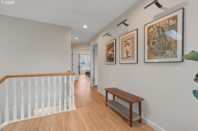 hall featuring an upstairs landing, recessed lighting, light wood-style flooring, and baseboards