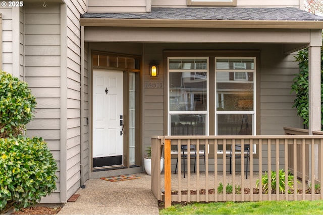 doorway to property with covered porch and a shingled roof