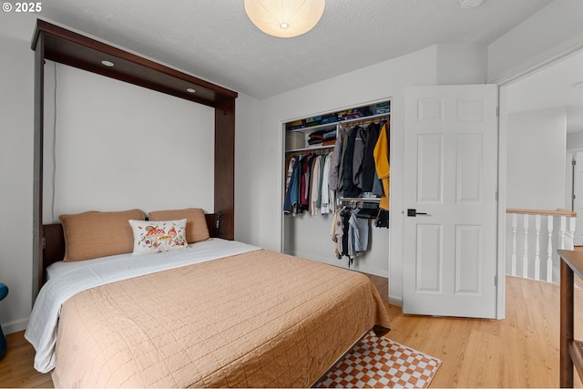 bedroom with light wood-type flooring, a textured ceiling, and a closet