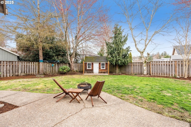 view of yard with a patio, a fire pit, a fenced backyard, and an outdoor structure