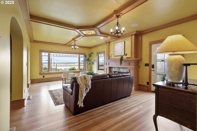 7506 SE Evergreen Hwy, Vancouver, WA 98664 - living room featuring a chandelier, light wood finished floors, a fireplace, ornamental molding, and arched walkways