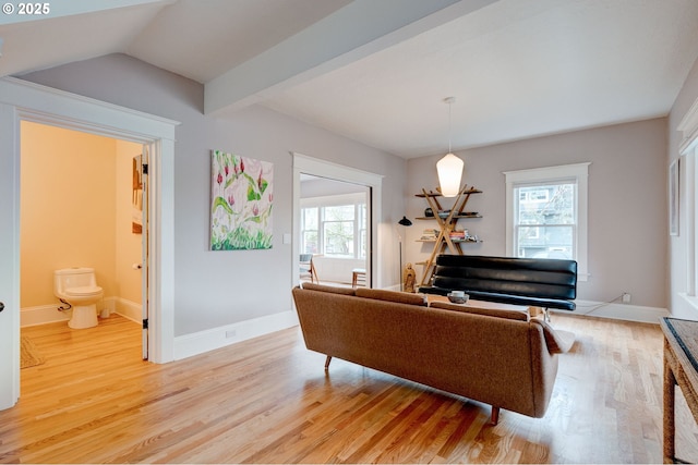 living area featuring light wood finished floors, plenty of natural light, lofted ceiling with beams, and baseboards