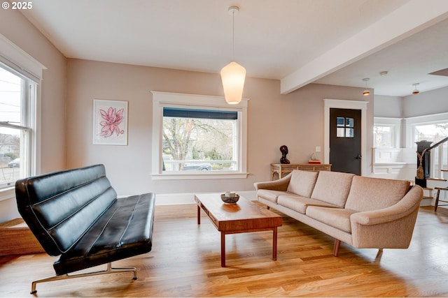 living room with a wealth of natural light, beam ceiling, stairs, and light wood-style floors