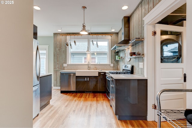 kitchen with appliances with stainless steel finishes, light wood-type flooring, light countertops, and a sink