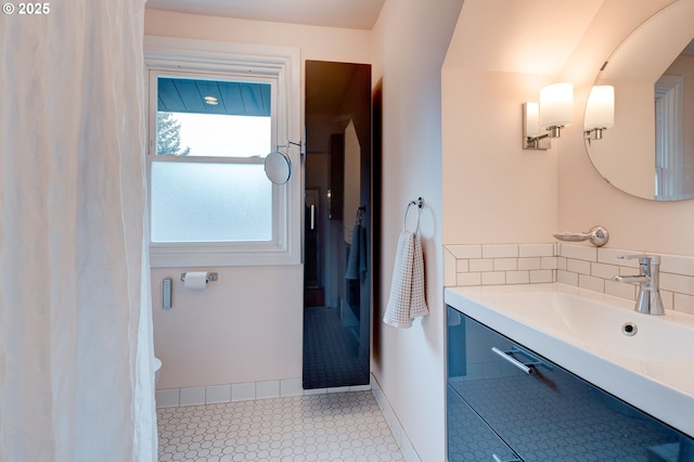 bathroom with a sink, baseboards, and backsplash