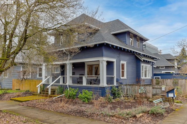 view of front of property with a porch, a shingled roof, and fence