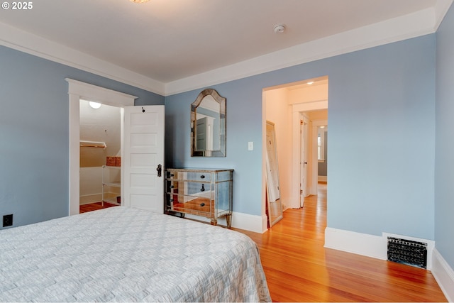 bedroom featuring visible vents, crown molding, light wood-type flooring, and baseboards