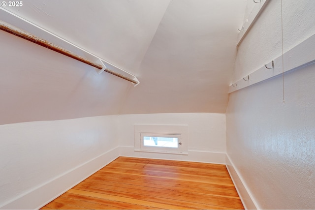 additional living space featuring light wood-type flooring, baseboards, and vaulted ceiling