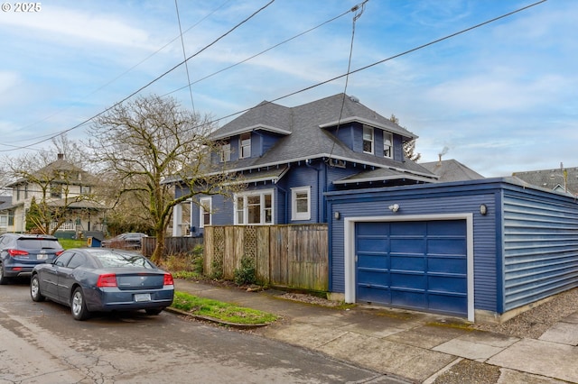 view of front of house featuring a shingled roof, an attached garage, and fence