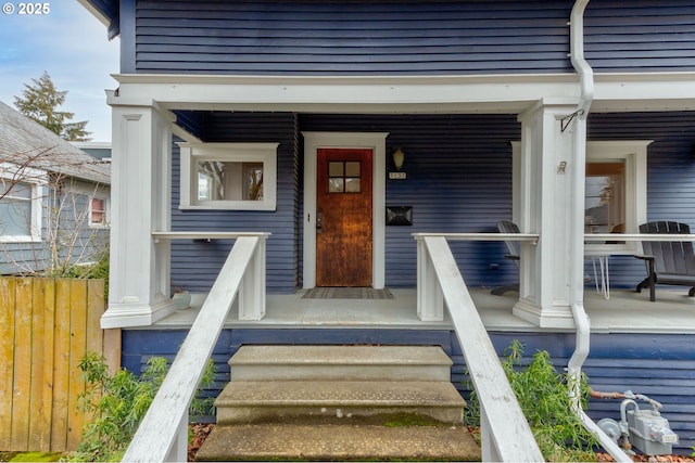 entrance to property featuring a porch and fence