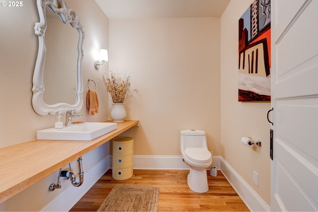 bathroom featuring toilet, vanity, baseboards, and wood finished floors