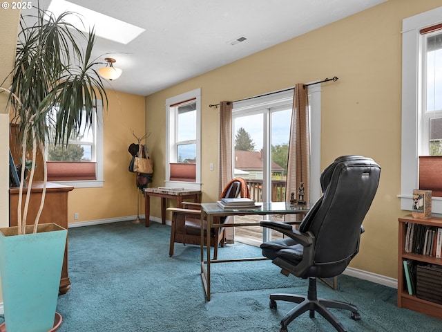 carpeted office space featuring a skylight, baseboards, and visible vents