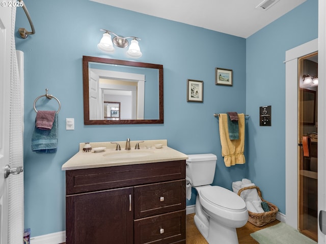 bathroom featuring baseboards, vanity, toilet, and visible vents