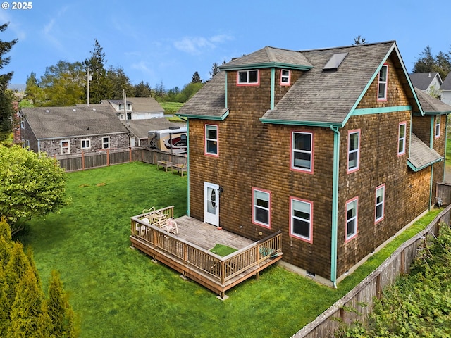 back of house featuring a fenced backyard, roof with shingles, a wooden deck, and a yard
