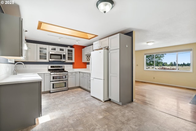 5425 SW Willow Ave, Corvallis, OR 97333 - kitchen with appliances with stainless steel finishes, glass insert cabinets, decorative backsplash, gray cabinets, and light countertops