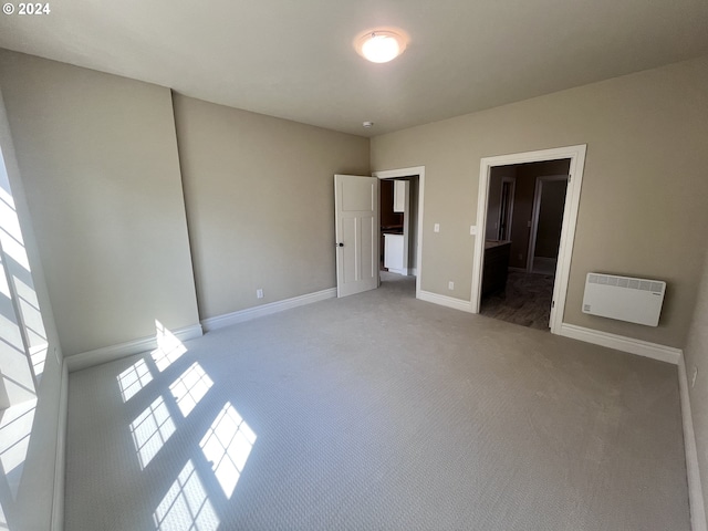 unfurnished bedroom with carpet flooring, a walk in closet, and heating unit