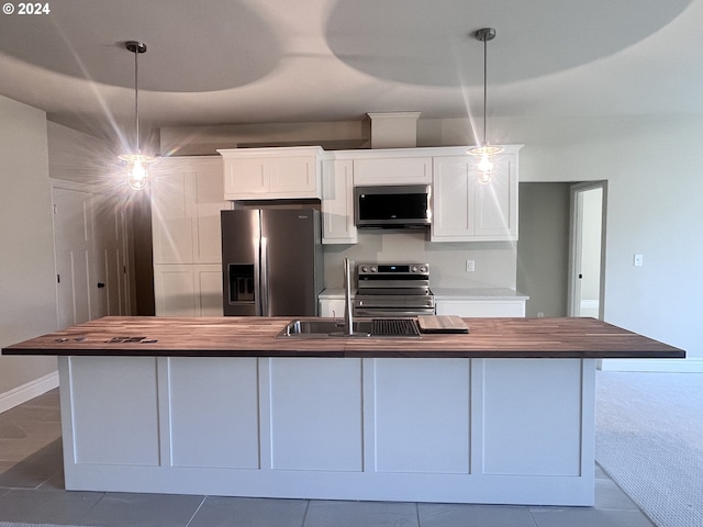 kitchen featuring white cabinets, decorative light fixtures, appliances with stainless steel finishes, and wooden counters